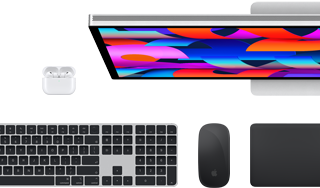En samling tillbehör och enheter: AirPods, Magic Keyboard med Touch ID, Magic Mouse, Magic Trackpad och Studio Display