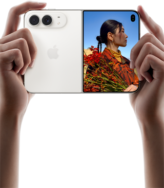 iPhone Duo, i färgen stjärnvit, hålls i två händer i stående läge, utfälld, den vänstra panelen visar 48 MP Fusion-dubbelkameran på baksidan, den högra panelen visar en person som blir fotograferad på den yttre skärmen, personen kan se sitt ansikte medan bilden tas med Duo Preview