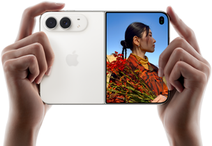 iPhone Duo, i färgen stjärnvit, hålls i två händer i stående läge, utfälld, den vänstra panelen visar 48 MP Fusion-dubbelkameran på baksidan, den högra panelen visar en person som blir fotograferad på den yttre skärmen, personen kan se sitt ansikte medan bilden tas med Duo Preview