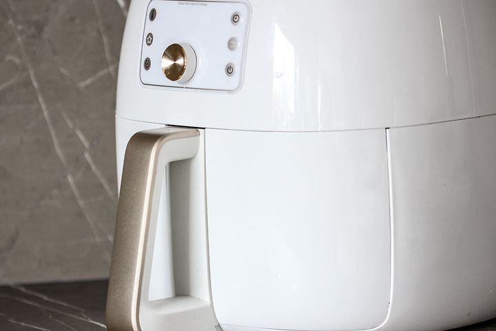 Närbild av en vit airfryer på en svart köksbänk