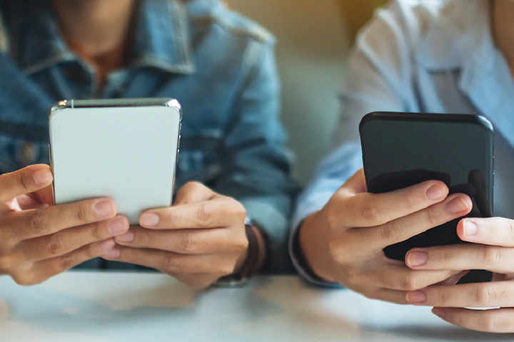 Tre personer som sitter med sina mobiltelefoner vid ett bord