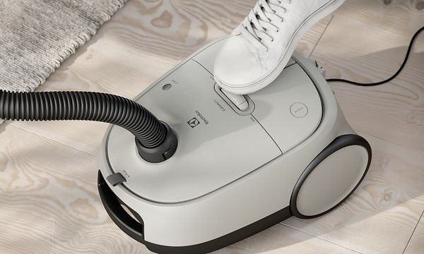 Electrolux Clean 600 Bagged vacuum cleaner in white and a human foot using the foot control