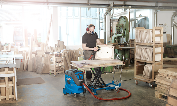 Man using professional Nilfisk vacuum in his woodshop