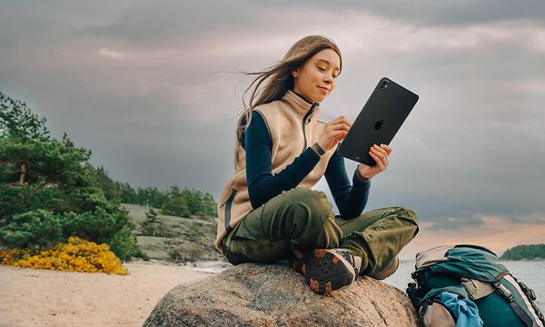 Woman sitting on a rock on the beach with an iPad