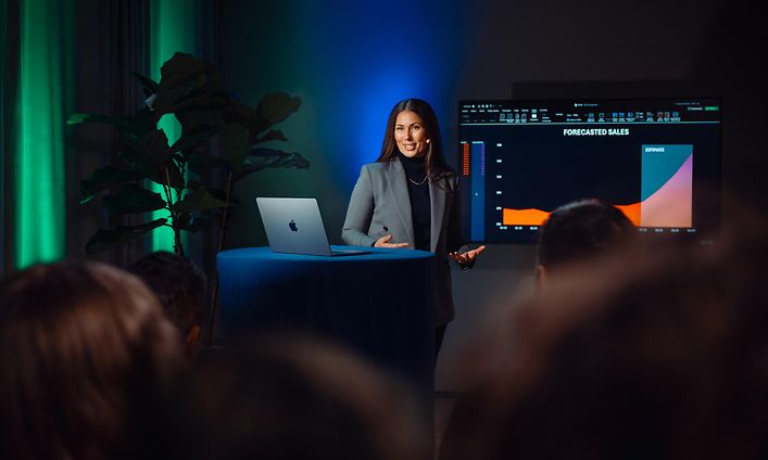 Kvinna som presenterar framför publiken med MacBook Air bredvid henne