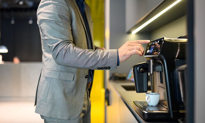 Man förbereder kaffe med kaffemaskinen på ett modernt kontor